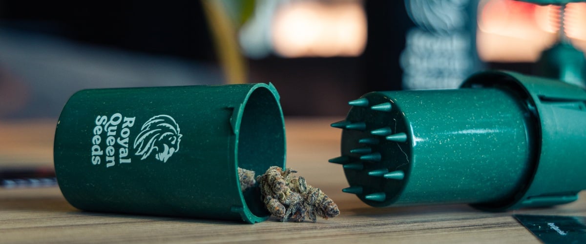 Grindtainer for Easy Cannabis Storage and Grinding Image of a compact grindtainer with cannabis buds on a wooden surface.
