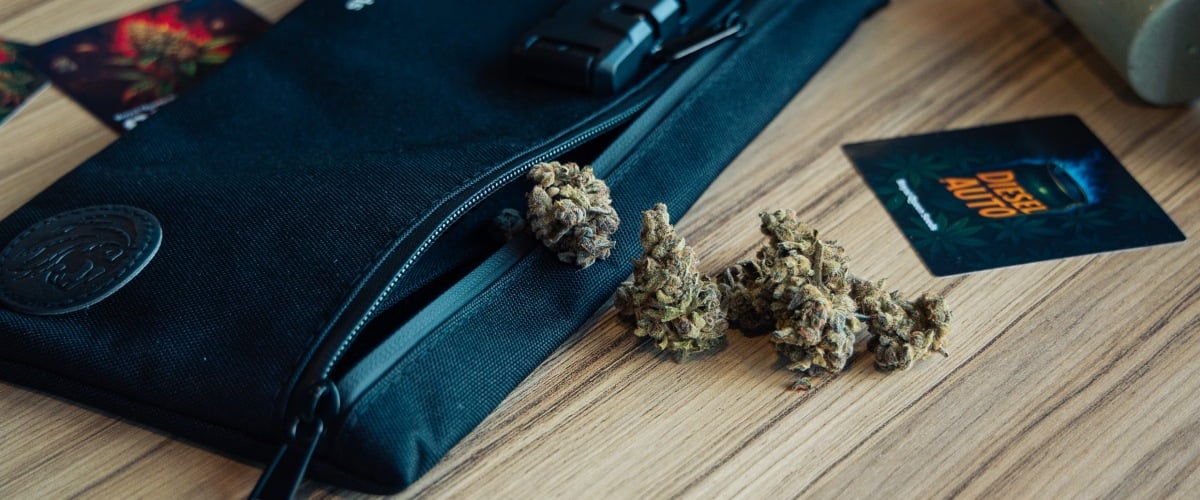 Discreet Stash Bag for Cannabis Storage Image of a lockable stash bag with cannabis buds on a wooden surface.